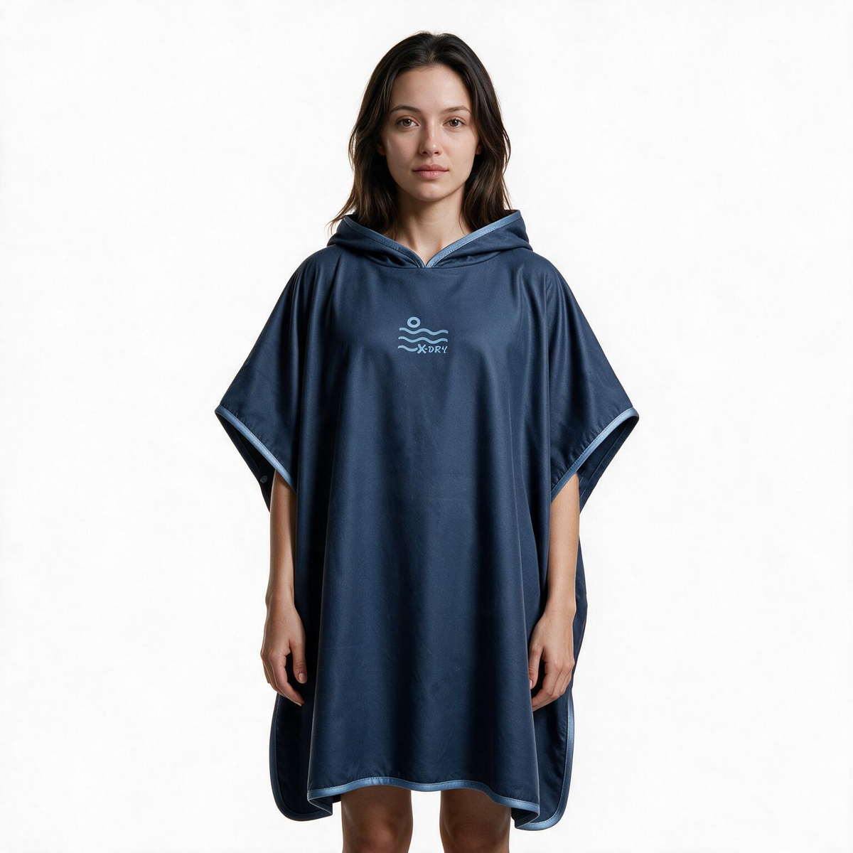 A woman modeling a navy blue hooded poncho with light blue trim and a small wave logo on the chest, set against a plain white background.